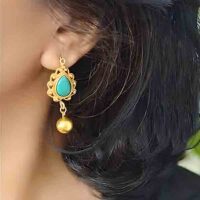 Model wearing Traditional ethno Tibetan gilded brass norbu earrings left
